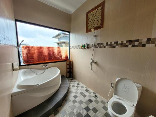 Un baño con inodoro, lavabo y ventana. en Ramantika Sunset Bay, en Nusa Dua