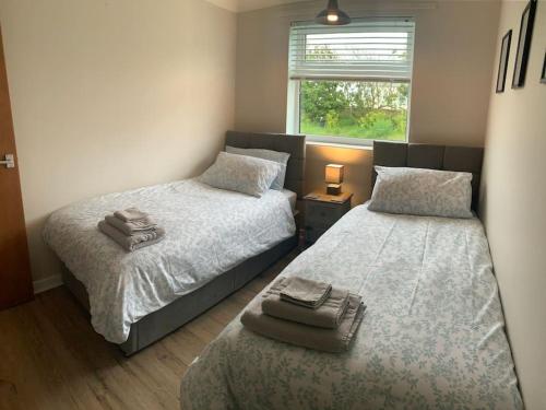 een slaapkamer met twee bedden en een raam bij Barley Break - Beach Cottage in Lessingham