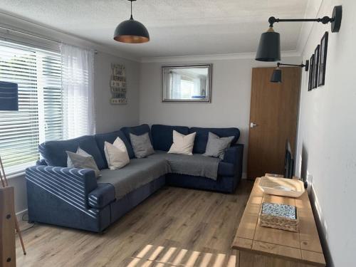 een woonkamer met een blauwe bank en een tafel bij Barley Break - Beach Cottage in Lessingham