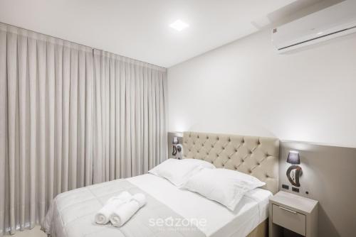 a bedroom with a bed with two towels on it at MHFA - Studios em Prédio Luxuoso com Vista Mar in Itapema