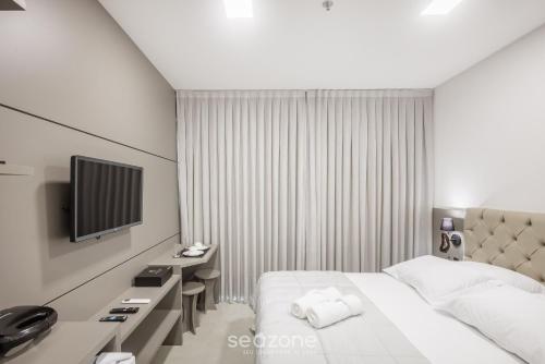 a hotel room with a bed and a television at MHFA - Studios em Prédio Luxuoso com Vista Mar in Itapema