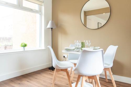 a dining room table with white chairs and a mirror at Moncrieff House in Livingston