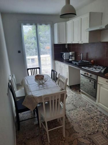 une cuisine avec une table et des chaises blanches, une table, une table et des chaises dans l'établissement Maison avec jardin, à Carcassonne