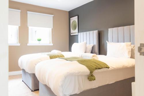 a bedroom with two beds with white sheets and windows at Moncrieff House in Livingston