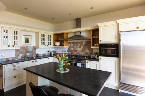 a kitchen with white cabinets and a black counter top at Balvraid Steading - Awesome views, near Dornoch in Dornoch