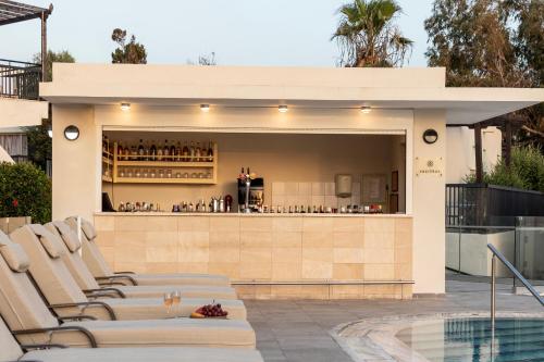 a bar on the side of a house with lounge chairs at Louis Paphos Breeze in Paphos City