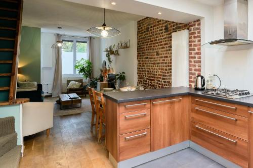 une cuisine avec des placards en bois et un mur en briques dans l'établissement Le Flore - Les Demeures d'Adrien, à La Madeleine