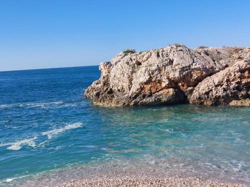 a beach with rocks and the ocean on a clear day at White Apartman in Dobra Voda