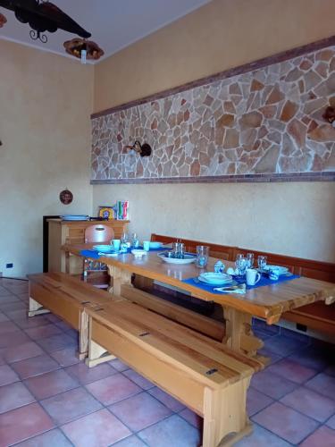 a dining room with a long wooden table and benches at Casa Roverelle in Aci SantʼAntonio