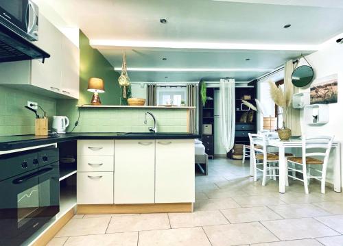 une cuisine avec des placards blancs et une salle à manger avec une table dans l'établissement Kaki Green Appartement Lumineux, Chic & Cosy WIFI Centre ville, à Chalencon