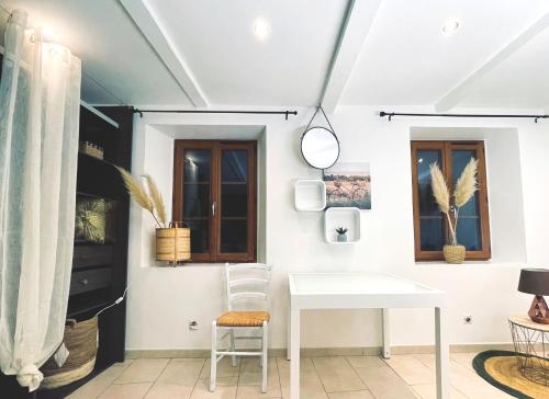 Cette chambre dispose d'une table blanche et de deux fenêtres. dans l'établissement Kaki Green Appartement Lumineux, Chic & Cosy WIFI Centre ville, à Chalencon