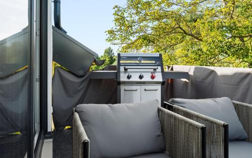 a grill sitting on a patio with two chairs at Lit Living Deluxe Apartments Wörth - Parking - Box Spring - BBQ - Balcony in Wörth am Rhein