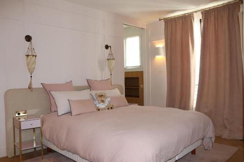 une chambre avec un grand lit blanc avec des oreillers roses dans l'établissement Luxueux Appartement avec balcon, Champs Élysées, à Paris