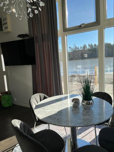 a table and chairs in a room with a large window at Beach Solsa in Nynäshamn