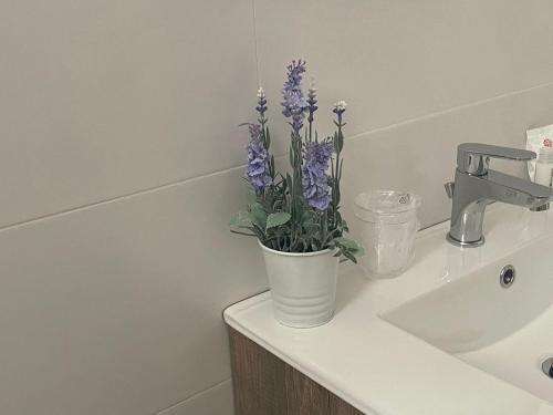 a white vase with purple flowers on a bathroom sink at Lazzara 19 in Marsala
