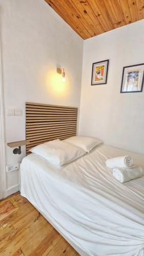 - un lit blanc dans une chambre dotée d'un plafond en bois dans l'établissement L'Histoire Clermontoise - Tramway au pied du logement, à Clermont-Ferrand