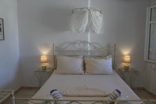 a bedroom with a white bed with two lamps at Villa Le Grand Bleu in Katapola