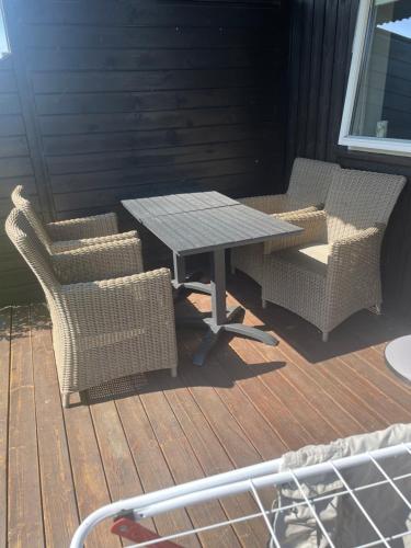 a picnic table and two chairs on a deck at Cozy apartment near Stavanger Airport in Sola