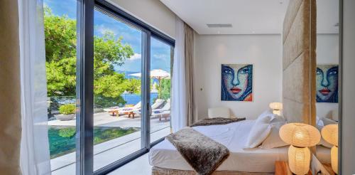 Un dormitorio con una cama y una gran ventana de cristal. en Villa Ivy - an award winning beachfront villa on the island of Brac near Split, en Selca