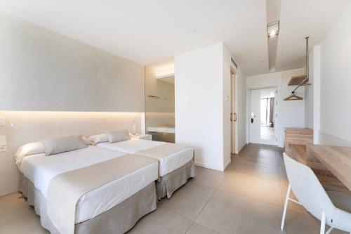 a white bedroom with a large bed and a table at Bordoy Cosmopolitan in Playa de Palma
