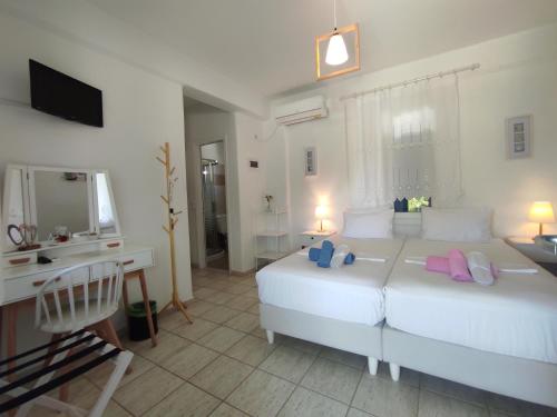 a white bedroom with a large bed and a desk at Villa Le Grand Bleu in Katapola