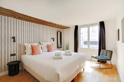une chambre avec un grand lit blanc et une chaise dans l'établissement Pick A Flat's Apartement in Saint-Martin - Rue du faubourg Saint-Martin, à Paris