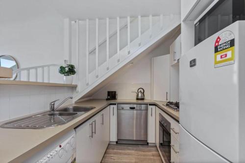 a white kitchen with a sink and a staircase at 9 Whitecrest Great Ocean Road Resort - Ocean View in Apollo Bay