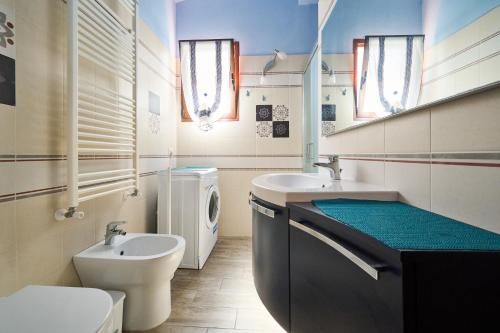 a bathroom with a toilet and a sink and a washing machine at San Vincenzo San Luigi 261 in San Vincenzo