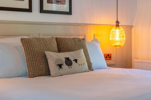 a bed with white sheets and a pillow with sheep on it at Woolpack Inn in Canterbury