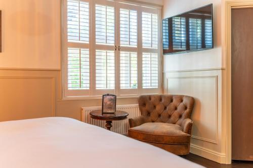 a bedroom with a bed and a chair and windows at Woolpack Inn in Canterbury