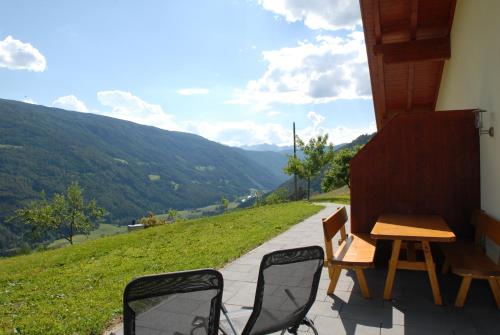 a table and chairs on a porch with a view of mountains at Appartament Eichnerhof in Chienes