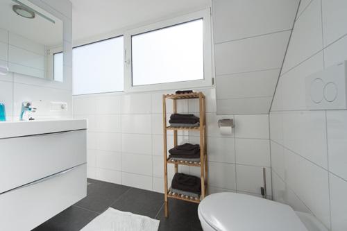 a bathroom with a toilet and a shelf with towels at Holiday Home D'arke in Westkapelle