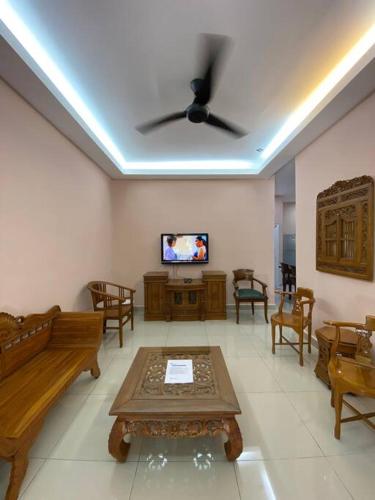 a living room with a ceiling fan and a tv at Homestay73 - Parit Raja in Parit Raja