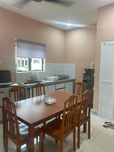 a kitchen with a wooden table and chairs in a room at Homestay73 - Parit Raja in Parit Raja
