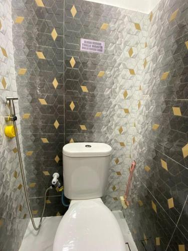 a bathroom with a white toilet in a tiled wall at Homestay73 - Parit Raja in Parit Raja