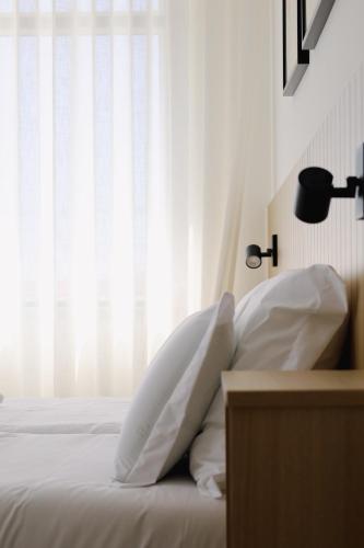 a bedroom with a bed with white sheets and a window at Casa d'Albarróis in Alenquer