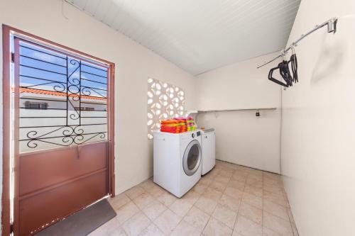 a laundry room with a washing machine and a door at Ierlandstraat 23 in Oranjestad