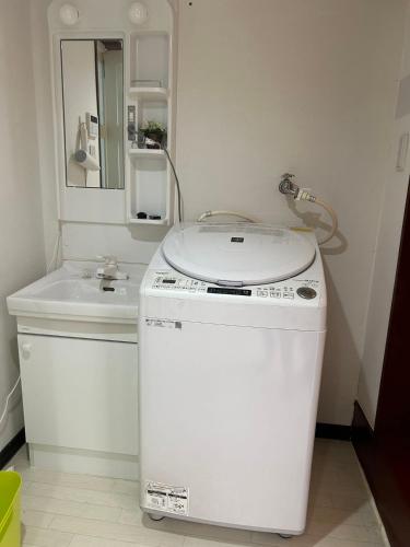 a small bathroom with a washing machine and a sink at 金の森民泊 in Osaka