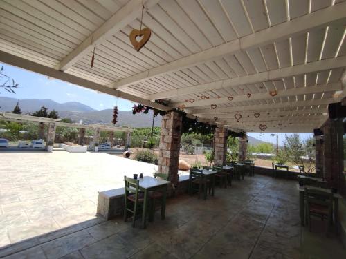 a patio with tables and chairs under a roof at Villa Le Grand Bleu in Katapola