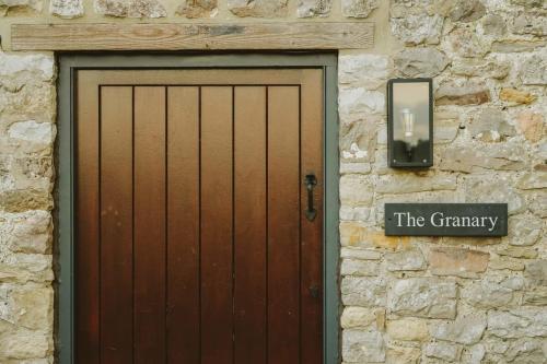 a wooden door with a sign on a stone wall at The Granary- Hopewell in Bristol