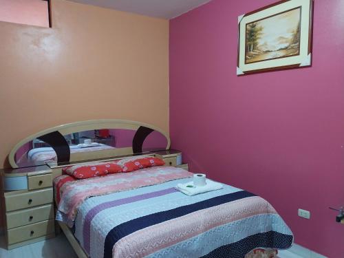 a bedroom with a bed and a pink wall at D203 in Moyobamba
