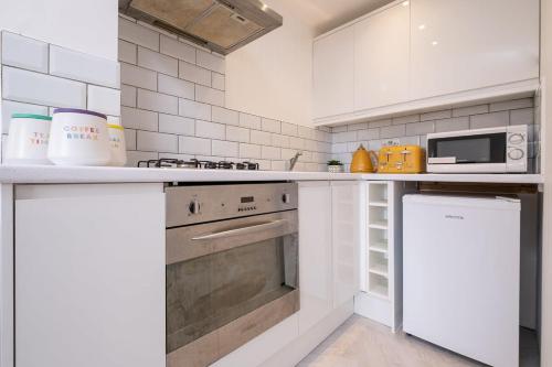 a white kitchen with a stove and a microwave at Host & Stay - Good Vibes at Buckingham in Brighton & Hove