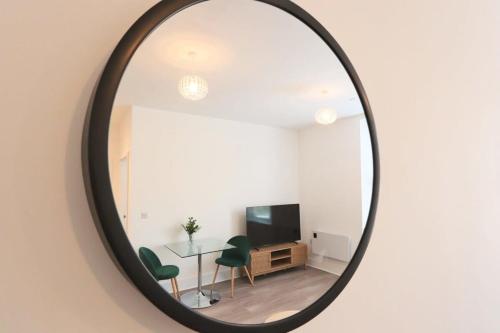 a mirror reflecting a living room with a table and a tv at Alliance 209 in Bristol