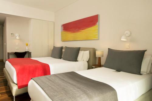 a hotel room with two beds and a red blanket at Palo Santo Hotel in Buenos Aires