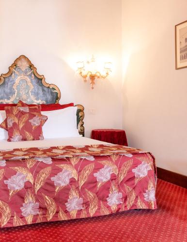 a bedroom with a bed with a red bedspread at Palazzetto Pisani Grand Canal in Venice