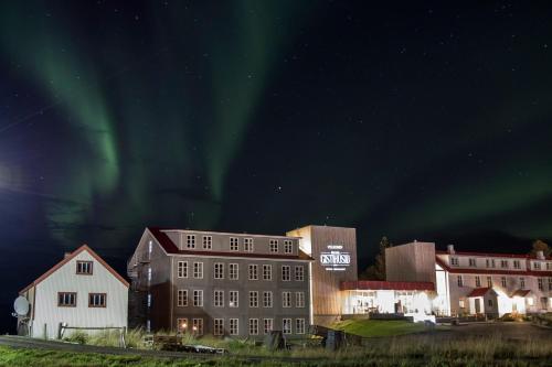 a group of buildings with the aurora in the sky at Gistihúsið - Lake Hotel Egilsstadir in Egilsstadir