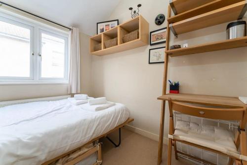 a bedroom with a bed and a window and shelves at Super central cosy & cute North Laine cottage in Brighton & Hove