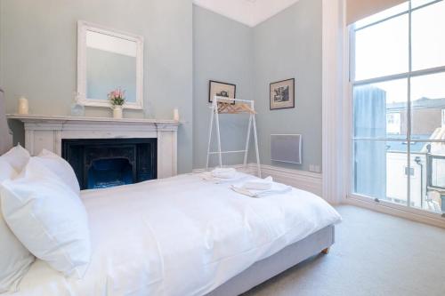 a white bedroom with a bed and a fireplace at Host & Stay - Brunswick Sea View in Brighton & Hove