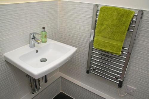 une salle de bain avec un lavabo et une serviette verte dans l'établissement Deluxe Townhouse Next to Cabot Circus, à Bristol