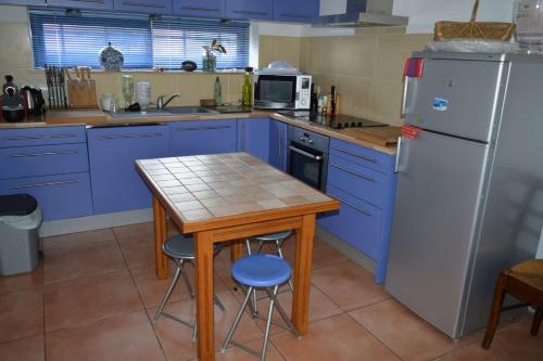 La cuisine est équipée de placards bleus, d'une table et d'un réfrigérateur. dans l'établissement Villa 4 pièces- Argelès sur mer AR000-021, à Argelès-sur-Mer